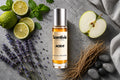 Aced It roll on bottle with Lime, Mint, Green Apple, Lavender, Vetiver roots and smooth stones on grey background