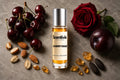 Cherry Issue Roll On bottle surrounded by cherries, red rose, plum, almonds, amber crystals and cacao beans on a stone background
