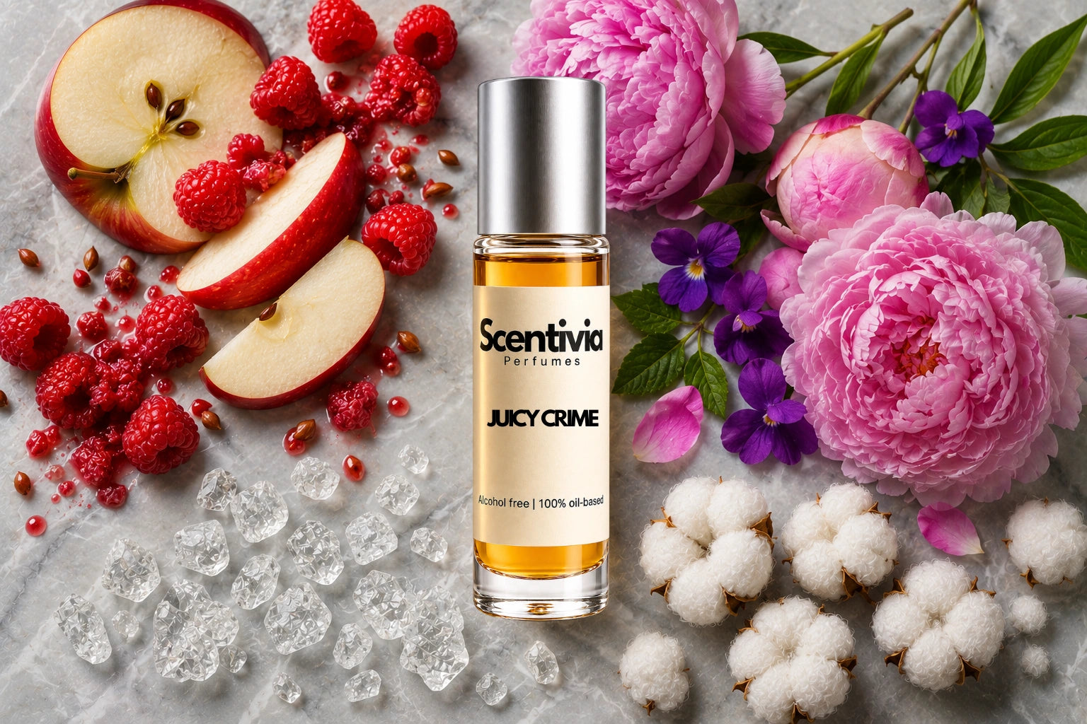 Juicy Crime Roll On bottle surrounded by red apple slices, raspberries, pink peonies, violet flowers, cotton blooms and crystal amber accents on a marble 
background