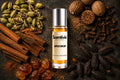 Spice Drop roll on bottle with Cardamom, Cinnamon, Cloves, Nutmeg, Vanilla beans and Amber crystals on dark background