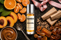 Sugar Spell roll on bottle with Orange slices, Peach, Caramel cream, Sandalwood and Amber crystals on dark background